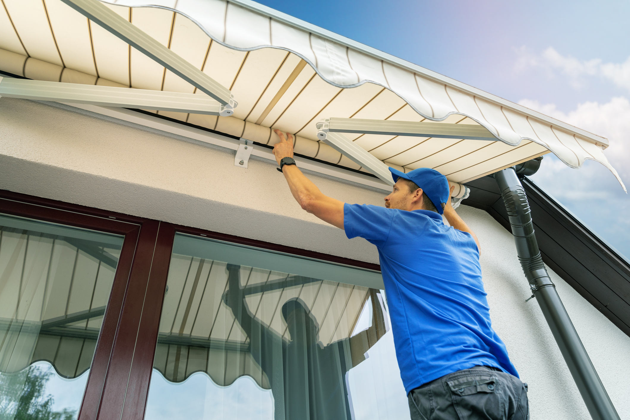 worker install an awning on the house wall over the terrace window